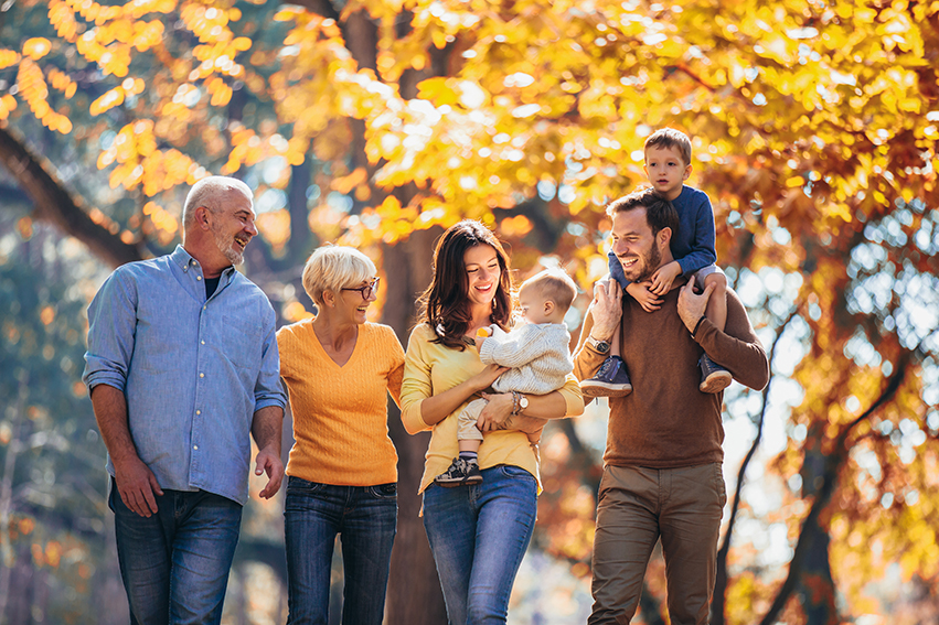 Multi generation family in autumn park having fun